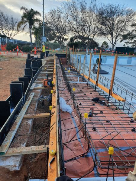 photograph of excavation on the side of the empty olympic pool where rebar and boarding is set up for concreting the accessibility ramp